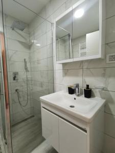 a white bathroom with a sink and a shower at Tri srca in Banja Koviljača
