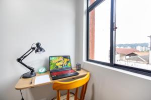 a laptop computer sitting on a desk next to a window at Centro Blumenau Rota Gastronômica Piscina in Blumenau