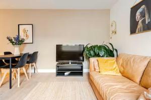 a living room with a couch and a table and a television at Tussen Tulp & Zee in Noordwijk