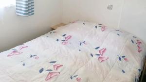 a white bed with pink butterflies on it at Bungalow charmant à Saint-Jean-de-Monts avec piscine partagée in Saint-Jean-de-Monts