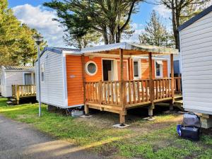 an orange and white tiny house next to a house at Bungalow charmant à Saint-Jean-de-Monts avec piscine partagée in Saint-Jean-de-Monts