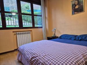 a bedroom with a bed with a checkered blanket and a window at Casa Marisol Blue 36A02 in Pola de Laviana