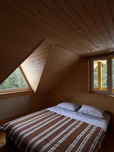 a bed in a wooden room with two windows at Котедж Зелениця in Zelenitsa