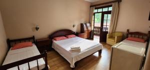 a bedroom with two beds and a table and a window at Hotel Floresta in Poços de Caldas
