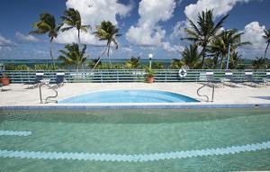 a swimming pool with chairs and the ocean in the background at Club St. Croix Beach and Tennis Resort in Christiansted