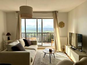 Una sala de estar con un sofá y una ventana grande. en Appartement terrasse vue mer/campagne, en Blonville-sur-Mer