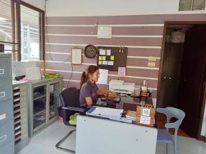 a woman sitting at a desk in a room at Goldenville in Ban Du