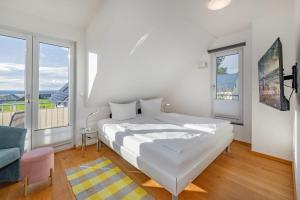 a white bedroom with a bed and a large window at Ferienhaus Adele in Ueckeritz