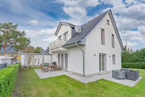 a white house with a patio and grass at Ferienhaus Adele in Ueckeritz