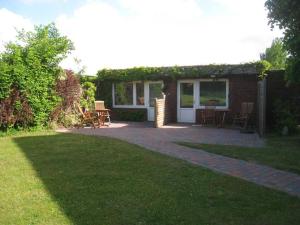 una casa con un patio con mesa y sillas en Haus Carstensen-Bungalow 3, en Wyk auf Föhr