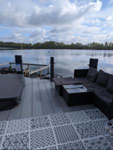 a couch sitting on a dock next to the water at Lakeside Lodge - Jet Ski Lake in Tattershall