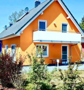an orange house with a table in front of it at Seeurlaub Müritz - Haus Nordlicht mit Sauna, Kamin, Wallbox, nur 250 m zum Strand in Röbel