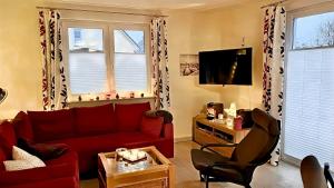 a living room with a red couch and a tv at Seeurlaub Müritz - Haus Nordlicht mit Sauna, Kamin, Wallbox, nur 250 m zum Strand in Röbel