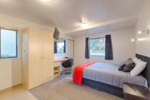 Schlafzimmer mit einem Bett, einem Schreibtisch und einem Fenster in der Unterkunft Bella Vista Motel Te Anau in Te Anau
