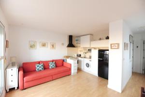 ein Wohnzimmer mit einem roten Sofa und einer Küche in der Unterkunft Atico Brisa in Cádiz
