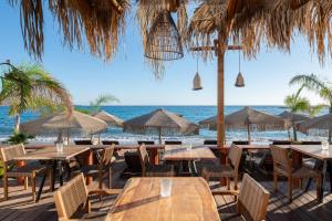 a restaurant on the beach with tables and umbrellas at Aquarius Beach Hotel in Faliraki