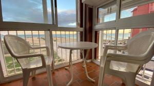 two chairs and a table in a room with windows at Beachfront apartment in La Mata in La Mata
