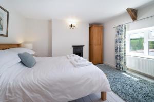 ein Schlafzimmer mit einem weißen Bett und einem Kamin in der Unterkunft Ford Hill Cottage in East Down