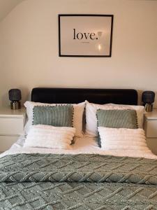 a bed with white pillows and a sign that says love at Beach Vista Apartment Three in Barmouth in Barmouth
