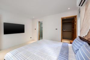 a bedroom with a bed and a tv on the wall at The Penthouses, Bangpor Seaview Luxury Apartment in Koh Samui  +6 photos