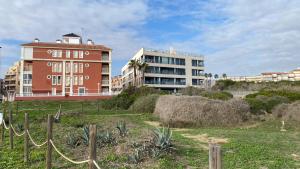a building with a fence in front of a field at Beachfront apartment in La Mata in La Mata