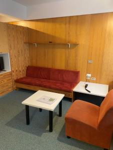 a living room with a red couch and a chair at Residence Solaria, Albarè, Marilleva 1400 in Marilleva