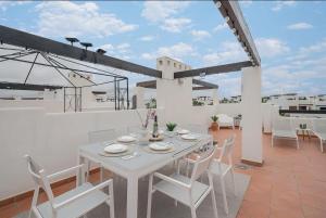 einen weißen Esstisch und Stühle auf dem Balkon in der Unterkunft Great Apartement & Golf With Big Roof Terrace in Alhama de Murcia