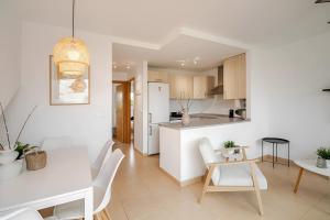 eine weiße Küche und ein Esszimmer mit Tisch und Stühlen in der Unterkunft Great Apartement & Golf With Big Roof Terrace in Alhama de Murcia
