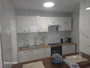 una cucina con mobili bianchi e un tavolo di legno di Los Gigantes apartment 113, 1 bedroom ad Acantilado de los Gigantes
