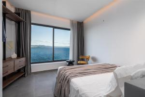 阿尔戈斯托利翁Almos Villas的一间卧室，里面有一张床和一扇大窗户。 更多68张照片