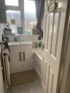 a bathroom with a sink and a white door at Convenient Home-stay in London