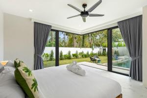 a bedroom with a white bed with a ceiling fan at Villa Gabriela Garden view - Included Airport pick up in Nathon Bay +82 photos