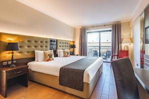 a hotel room with a large bed and a balcony at AX The Victoria Hotel in Sliema
