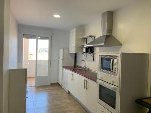 a kitchen with white cabinets and a microwave at Apartamento JALAMA 1C in Moraleja