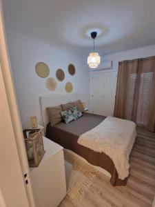 a small bedroom with a bed and a chandelier at Apartamento em Quarteira in Quarteira