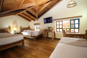 a bedroom with two beds and a tv on the wall at Hotel Boutique Vieja Cuba in Quito