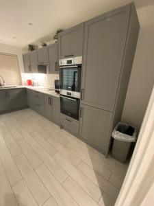 a kitchen with gray cabinets and a tile floor at Winter double bedroom in Stone Grove