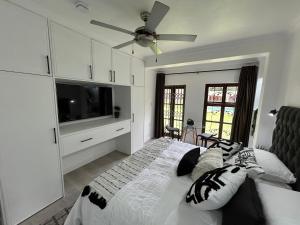 约翰内斯堡The Bryanston Boutique的一间带床和吊扇的白色卧室