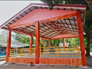 a red pavilion with a person walking in the distance at Nawal Raymundo Resort in Santa Cruz