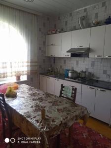 a kitchen with a table and chairs and a kitchen with white cabinets at LAZA DAĞ Evİ in Qusar