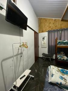 Cette chambre dispose d'une télévision murale et d'un lit. dans l'établissement Kitnet Girassol, à São Thomé das Letras