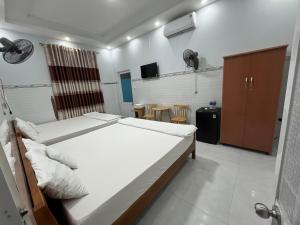 a bedroom with two beds and a tv in it at HÒANG HÔN HOMESTAY in Ben Tre
