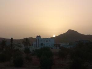 a sunset over a white building with a mountain in the background at Elmoubaraka2 in Tataouine
