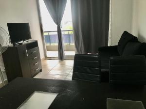 a living room with a black couch and a television at 3-Genial dpto morón centro in Morón