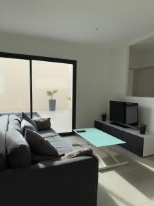a living room with a couch and a tv at La villa Kalima T3 in Sérignan