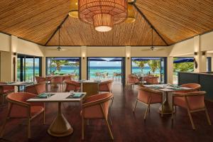 a restaurant with tables and chairs and the ocean at Sheraton Resort & Spa, Tokoriki Island, Fiji in Tokoriki