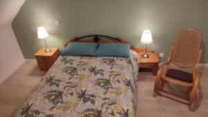 1 dormitorio con 1 cama con 2 lámparas y 1 silla en les hirondelles, en Péaule