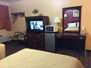 um quarto de hotel com uma televisão, uma cama e um espelho em Holiday Lodge em Pittsburg