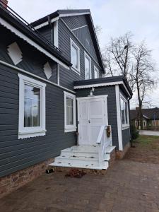 una casa nera con una porta bianca e un portico di Stebuklėlis a Pakruojis
