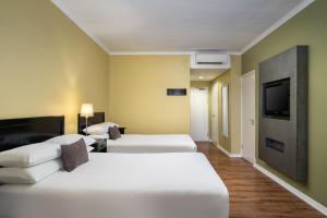 a hotel room with two beds and a flat screen tv at Protea Hotel by Marriott Bloemfontein in Bloemfontein